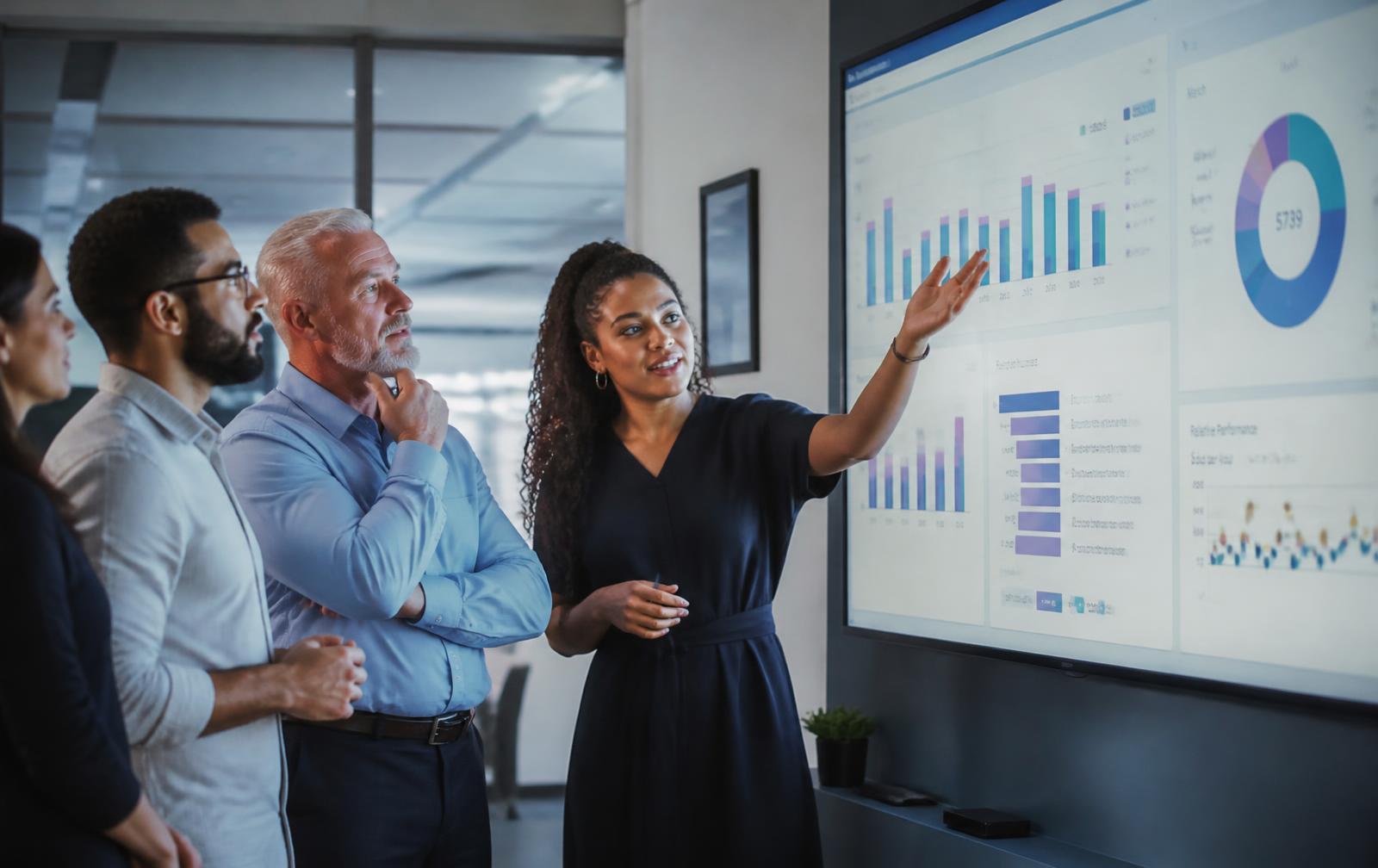 A diverse leadership team reviewing business dashboards together in a modern office